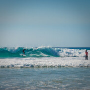 surfer ćwiczy manewr backside cutback, otrzymując instrukcje od trenera przez kask z radiem