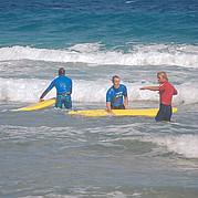 Instruktor surfingu wyjaśnia właściwą pozycję na desce surfingowej